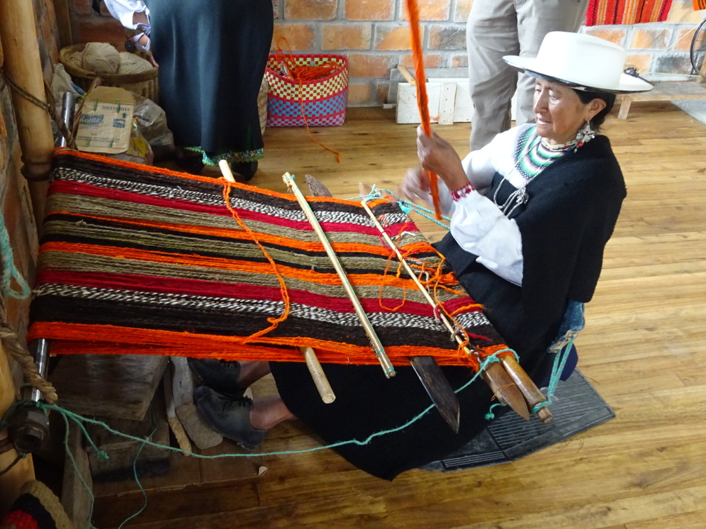 Abellina at the seated loom. She has a rough wood support behind her lower back which pulls the loom taut when she leans back. If you're curious, this is being woven with both natural and synthetic dyed wools.
