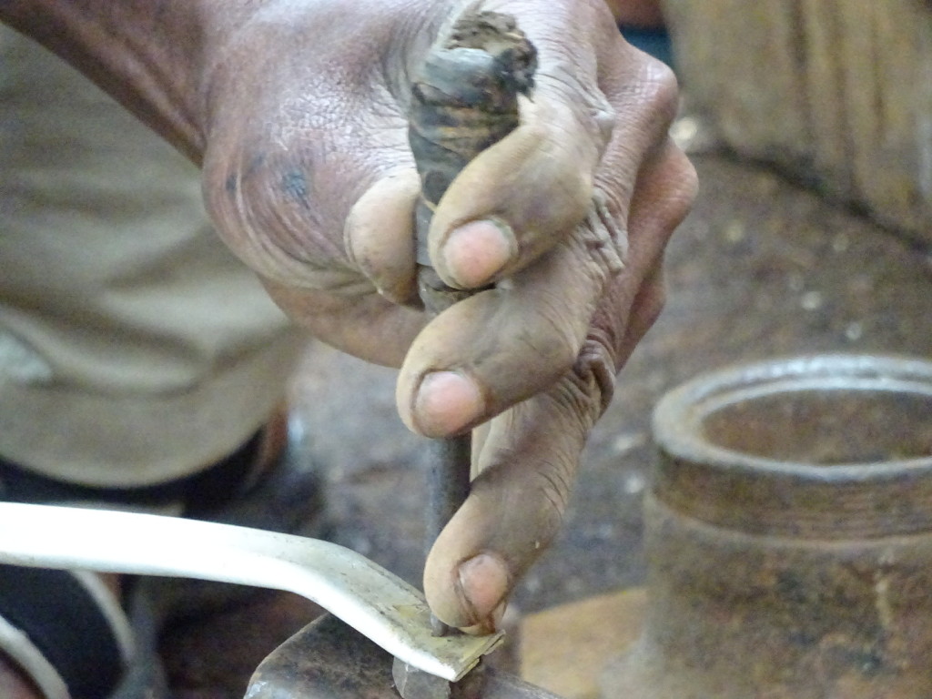 Punching holes in the handle to then rivet on the bowl. The punch is repurposed from a bicycle pedal center.