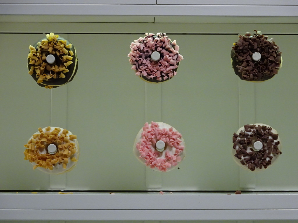 There is an entire wall behind the register with fancy donuts on pegs. They reflect in a wall sized mirror where the queue forms.