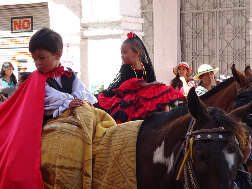 There were many horses topped with little children in traditional costume. The dresses and capes cover the entire horse!