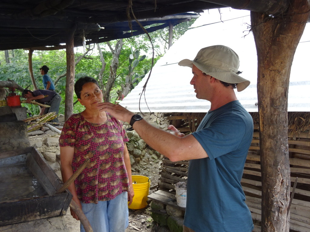 Talking with one of the brother's wives. She cooks down the juice from the sugar cane.
