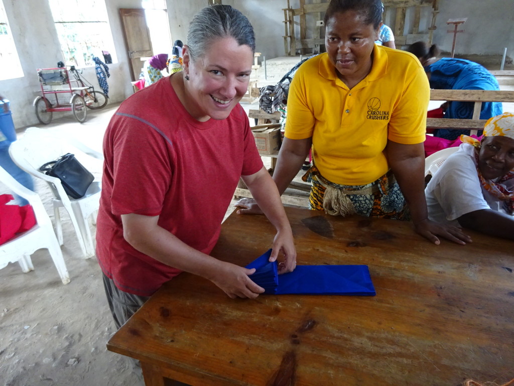Anner get a lesson in fabric folding. The triangle is called "sambusa" after a triangle shapped food here in TZ.